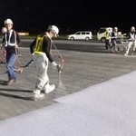 　滑走路の誘導路を舗装する作業員＝７日未明、成田空港（ＮＡＡ提供）