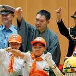 　警視庁神田署の交通安全啓発イベントで腕を振り上げる、講談師の神田伯山さん（後列中央）と高橋建次署長（同左）ら＝７日午後、東京都千代田区