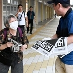 　石破首相が辞任の意向を固めたことを伝える号外を受け取る女性＝７日午後５時１９分、ＪＲ鳥取駅前