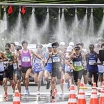 　北海道マラソンで、ミストシャワーをくぐるランナー＝８月、札幌市