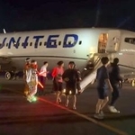 　関西空港に緊急着陸したユナイテッド航空機から、脱出用シューターを使って避難する乗客ら＝１２日夜（乗客提供）