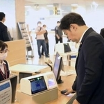 　スマホ保険証を使った受け付けを体験する福岡厚労相（手前右）＝７月、東京都目黒区の東京医療センター
