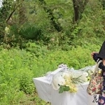 　愛知県犬山市の「入鹿池」のそばで献花し、手を合わせる女性＝１４日午前