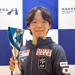 　トロフィーを手に撮影に応じるフィギュアスケート男子の鍵山優真＝１６日、羽田空港