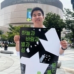 　映画「空と風と星と島」のポスターを手にする金明允さん＝１９日、韓国・釜山（共同）