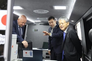 　ウクライナ・キーウで、寄贈した車両について話す中込正志大使（右）ら＝９月３０日（共同）