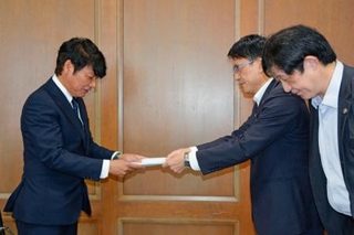 　佐賀県議会議長（左）に要望書を提出する県弁護士会の半田望弁護士（右手前）ら＝１日午前、佐賀市