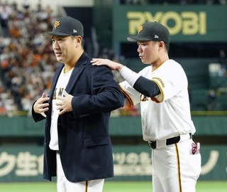 　日米通算２００勝達成を記念するセレモニーで、坂本勇人内野手（右）から受け取った名球会ブレザーを着る巨人・田中将大投手＝１日、東京ドーム