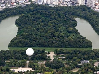 　仁徳天皇陵古墳（奥）近くの大仙公園から浮かび上がったガス気球＝３日午後、堺市（共同通信社ヘリから）