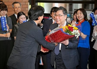 　ノーベル生理学・医学賞の受賞決定から一夜明け、大阪大の熊ノ郷淳学長（左）から花束を受け取る坂口志文特任教授＝７日朝、大阪府吹田市