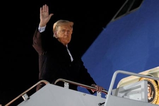 　２４日、米大統領専用機に乗り込む前に手を上げるトランプ大統領＝ワシントン郊外（ロイター＝共同）