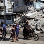 　４日、ガザ中部で、イスラエルによって破壊された建物のそばを歩く人々（ロイター＝共同）