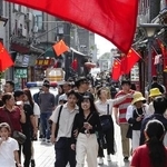 　国慶節を迎え、中国国旗が掲げられた北京市内の観光地を歩く人たち＝１日