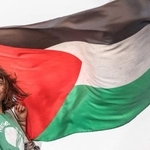 　ガザに向かう支援船に乗り、パレスチナの旗の隣でポーズをとるグレタ・トゥンベリさん＝９月２５日、ギリシャ・クレタ島沖（ロイター＝共同）