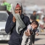 　１日、イスラエルの攻撃が激化し、赤ちゃんを抱えて逃げるパレスチナ人の女性＝ガザ北部ガザ市（ゲッティ＝共同）