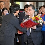 　ノーベル生理学・医学賞の受賞決定から一夜明け、大阪大の熊ノ郷淳学長（左）から花束を受け取る坂口志文特任教授＝７日朝、大阪府吹田市