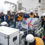 　巡視船の甲板に積み込んだ通信機材をベルトで固定する海上保安庁の隊員ら＝８日午後、富山県射水市