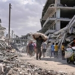 　ガザ南部ハンユニスで荷物を持って歩く人たち。イスラエルとイスラム組織ハマスの停戦が発効した＝１０日（ＡＰ＝共同）