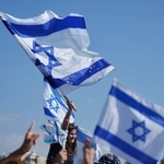 　イスラエルの国旗を持つ人たち＝１３日、イスラエル・テルアビブ近郊（ＡＰ＝共同）