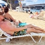 　真夏日となった那覇市の「波の上ビーチ」でくつろぐ外国人観光客ら＝１７日午後
