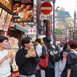 　横浜中華街の店先でフライドチキンを食べる男性＝１７日、横浜市