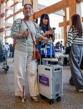 　大阪・関西万博会場で「ＡＩスーツケース」の実証実験に参加した久保田真智子さん（左）＝１０月、大阪市此花区の夢洲