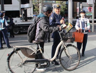 　自転車との違いを記したチラシを配布し、モペットに関する注意を喚起する警察官＝４日午後、東京・六本木