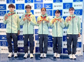 　トランポリンの世界選手権から帰国し、メダルを手に撮影に応じる宮野隼人（左から２人目）、田中沙季（同４人目）ら＝１１日、羽田空港