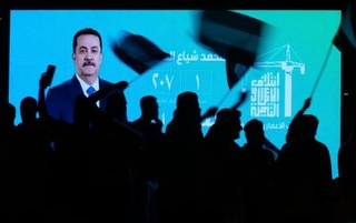 　イラクのスダニ首相が映ったスクリーン前で、選挙結果を喜ぶ支持者＝１２日、バグダッド（ＡＰ＝共同）