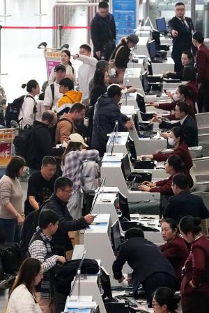 　北京首都空港の日本便などを扱うカウンターで搭乗手続きをする人たち＝１５日（共同）