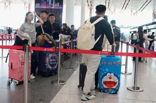 　北京首都国際空港の日本便などを扱うカウンターに並ぶ人たち＝１６日（共同）