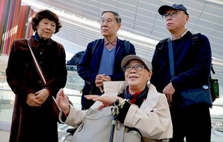 　米国への出発前、取材に応じる被爆者団体「長崎県被爆者手帳友の会」の代表団のメンバー。中央奥は朝長万左男さん＝２７日午前、羽田空港