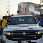 　１０月３０日、パレスチナ自治区ガザ中部で、ハマスが引き渡した２人の遺体を乗せた赤十字車両を見る子どもたち（ＡＰ＝共同）