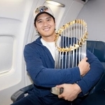 　ロサンゼルスへ移動する機内で優勝トロフィーを抱くドジャース・大谷（ドジャースの球団公式Ｘから）
