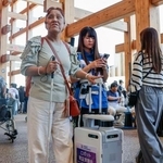 　大阪・関西万博会場で「ＡＩスーツケース」の実証実験に参加した久保田真智子さん（左）＝１０月、大阪市此花区の夢洲