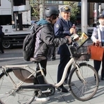 　自転車との違いを記したチラシを配布し、モペットに関する注意を喚起する警察官＝４日午後、東京・六本木
