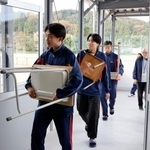 　石川県輪島市の県立門前高で、完成した仮設校舎に勉強机や椅子を運び込む生徒たち＝５日午前
