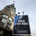 　５日、パリの百貨店前で抗議デモ参加者が掲げた「ＳＨＥＩＮ」を拒否するプラカード（ロイター＝共同）