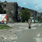 　ロシア軍の攻撃を受けた建物の近くを歩く住民＝５月、ウクライナ東部ドネツク州ポクロウシク（ロイター＝共同）