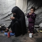 　６日、ガザ中部デールバラハのテントで避難生活を送る女性と子ども（ゲッティ＝共同）