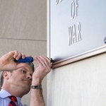 　米ワシントン近郊の国防総省入り口で、看板をかけ替えるヘグセス長官＝１３日（国防総省提供・共同）