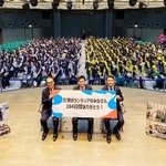 　大阪・関西万博の運営を支えたボランティアスタッフと写真に納まる万博協会の石毛博行事務総長（壇上左）ら＝１５日午後、大阪市北区