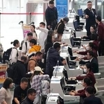 　北京首都空港の日本便などを扱うカウンターで搭乗手続きをする人たち＝１５日（共同）