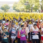 　神戸マラソンのスタート前、復興の象徴のヒマワリを表した黄色の手袋を掲げるランナー＝１６日午前、神戸市中央区