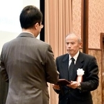 　「地域貢献大賞」の表彰式で日本新聞協会の中村史郎会長（左）から大賞の記念の盾を受け取る北國新聞宝立販売所の船本寛所長＝２０日午後、東京都千代田区