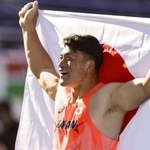 　男子円盤投げで優勝し、笑顔で日の丸を掲げる湯上剛輝＝駒沢陸上競技場