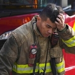 　消火活動が続く高層住宅の火災現場で頭に手をやる消防士＝２８日、香港北部・新界地区大埔（共同）