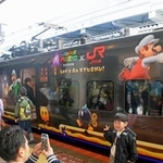 　特別ラッピング列車「スーパーマリオトレイン」の前で記念撮影する人たち＝２９日午前、ＪＲ博多駅