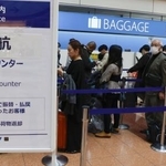 　国内線で欠航が発生し、全日空のカウンターに並ぶ人たち＝２９日午後０時４９分、羽田空港