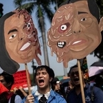 　マルコス大統領とサラ・ドゥテルテ副大統領のイラストを掲げ、抗議するデモ参加者ら＝３０日、マニラ（ロイター＝共同）